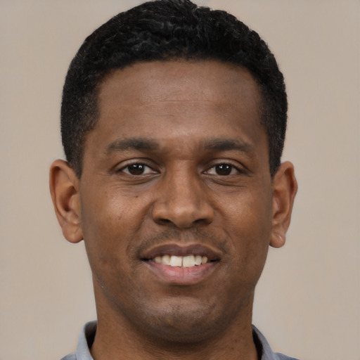 Joyful black young-adult male with short  black hair and brown eyes