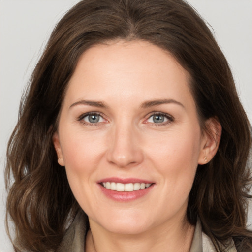 Joyful white adult female with medium  brown hair and grey eyes