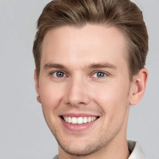 Joyful white young-adult male with short  brown hair and grey eyes