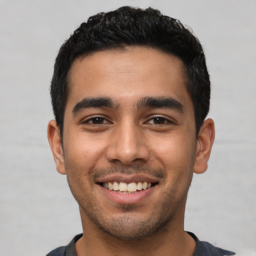 Joyful latino young-adult male with short  black hair and brown eyes