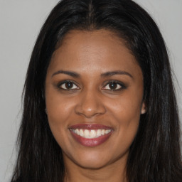 Joyful black young-adult female with long  brown hair and brown eyes