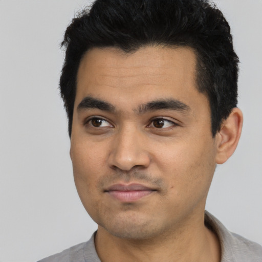 Joyful latino young-adult male with short  black hair and brown eyes