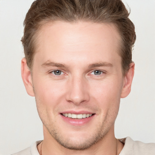 Joyful white young-adult male with short  brown hair and grey eyes