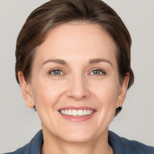 Joyful white young-adult female with medium  brown hair and grey eyes