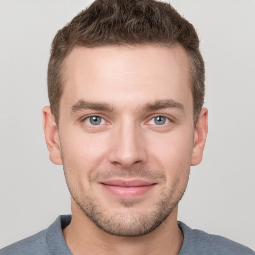 Joyful white young-adult male with short  brown hair and grey eyes