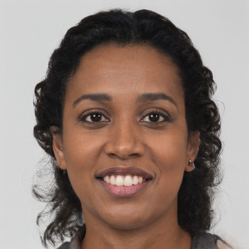 Joyful black young-adult female with medium  black hair and brown eyes