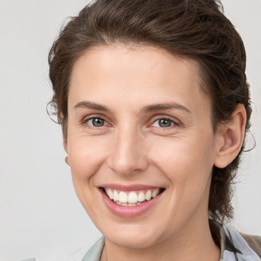 Joyful white young-adult female with short  brown hair and grey eyes