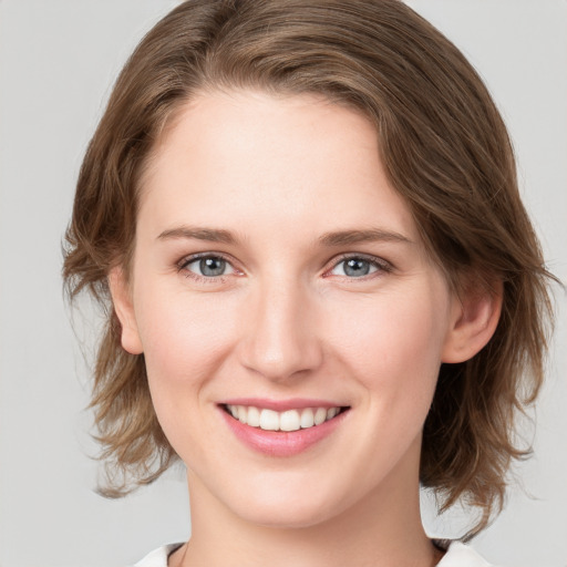 Joyful white young-adult female with medium  brown hair and grey eyes