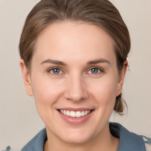 Joyful white young-adult female with medium  brown hair and grey eyes