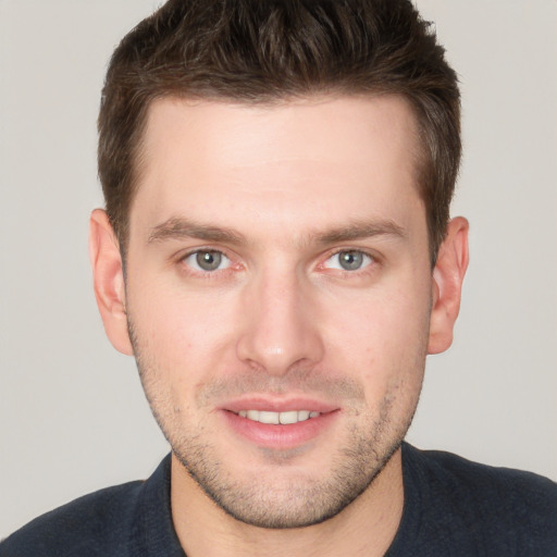 Joyful white young-adult male with short  brown hair and grey eyes