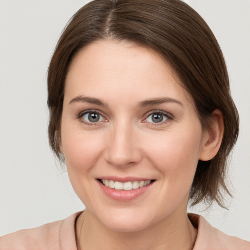 Joyful white young-adult female with medium  brown hair and grey eyes