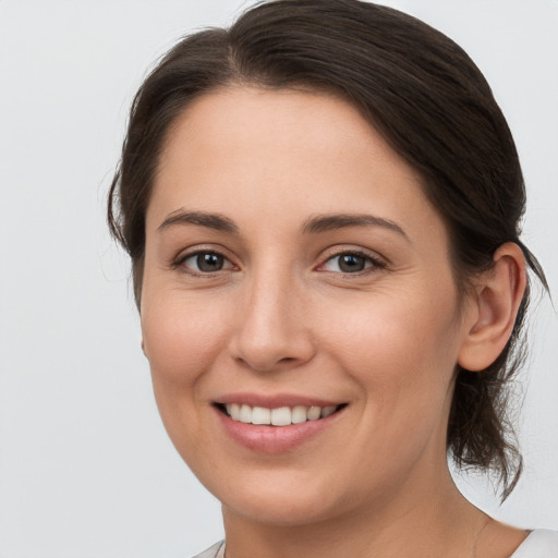 Joyful white young-adult female with medium  brown hair and grey eyes