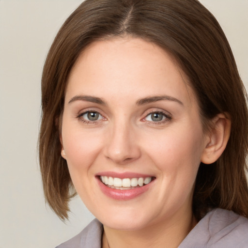 Joyful white young-adult female with medium  brown hair and grey eyes