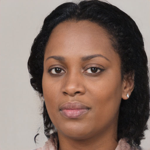 Joyful black young-adult female with long  black hair and brown eyes