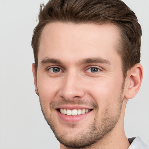 Joyful white young-adult male with short  brown hair and grey eyes