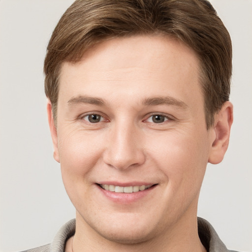 Joyful white young-adult male with short  brown hair and grey eyes