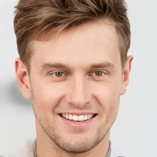 Joyful white young-adult male with short  brown hair and grey eyes