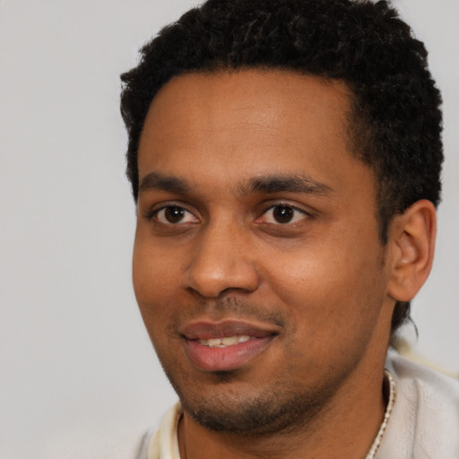 Joyful black young-adult male with short  black hair and brown eyes