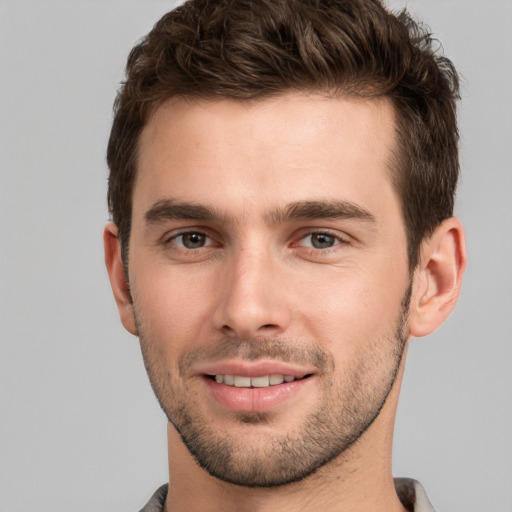 Joyful white young-adult male with short  brown hair and grey eyes