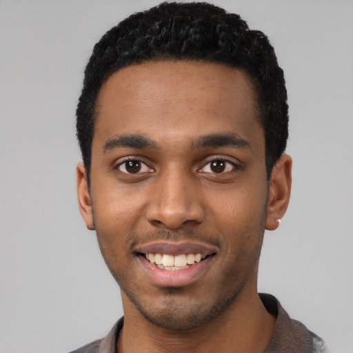 Joyful black young-adult male with short  black hair and brown eyes