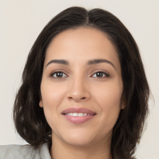 Joyful latino young-adult female with long  brown hair and brown eyes