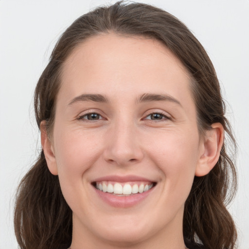 Joyful white young-adult female with medium  brown hair and grey eyes