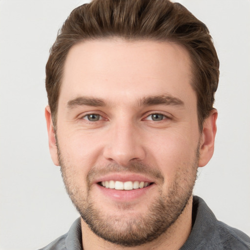 Joyful white young-adult male with short  brown hair and grey eyes