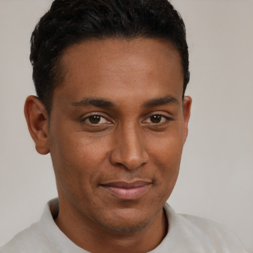 Joyful black young-adult male with short  brown hair and brown eyes