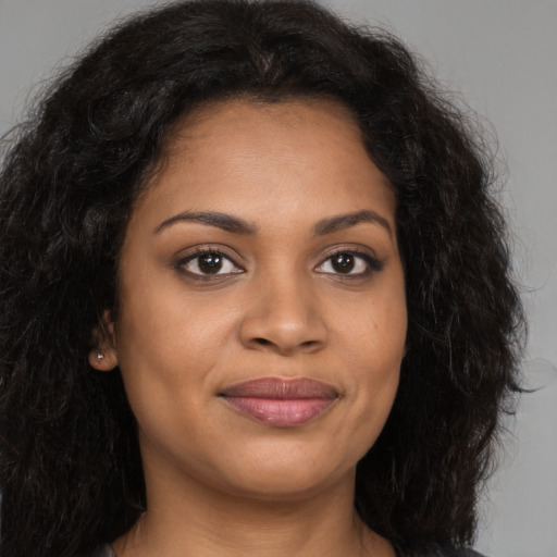 Joyful black young-adult female with long  brown hair and brown eyes