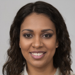 Joyful black young-adult female with long  brown hair and brown eyes