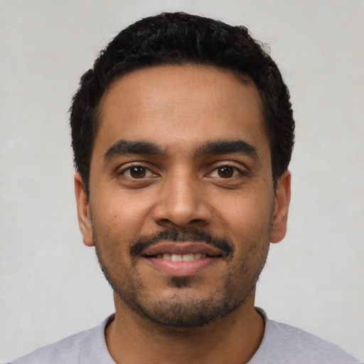 Joyful latino young-adult male with short  black hair and brown eyes