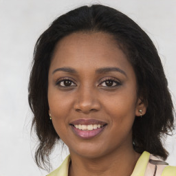 Joyful black young-adult female with long  brown hair and brown eyes