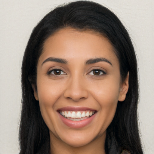 Joyful latino young-adult female with long  brown hair and brown eyes