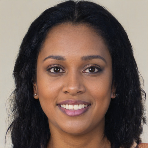 Joyful black young-adult female with long  black hair and brown eyes