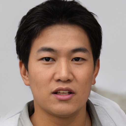Joyful asian young-adult male with short  brown hair and brown eyes