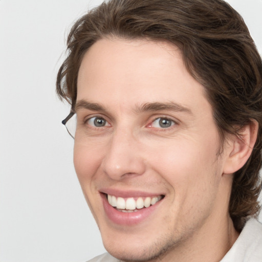 Joyful white young-adult male with medium  brown hair and grey eyes