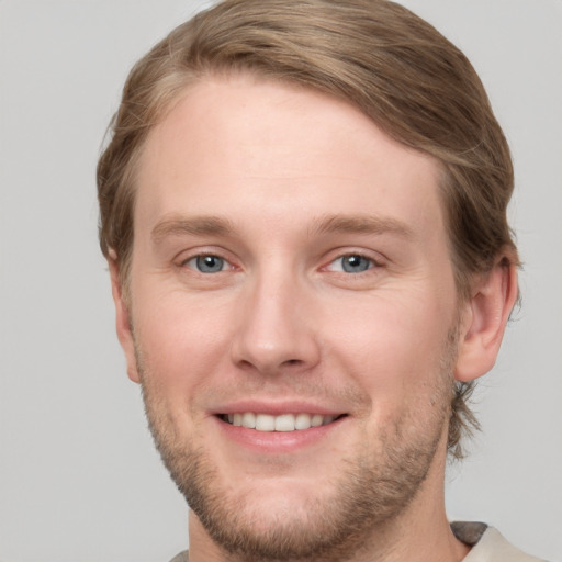 Joyful white young-adult male with short  brown hair and grey eyes