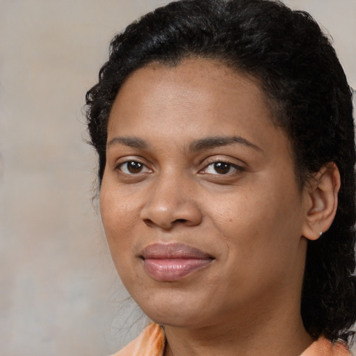 Joyful black young-adult female with long  brown hair and brown eyes