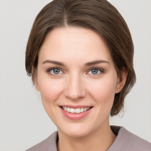 Joyful white young-adult female with medium  brown hair and grey eyes