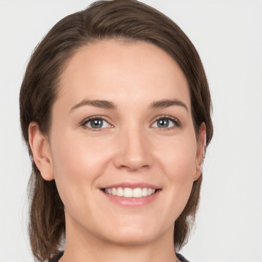 Joyful white young-adult female with medium  brown hair and grey eyes