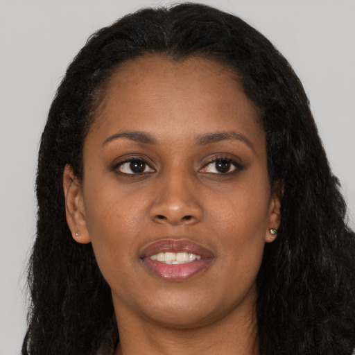 Joyful black young-adult female with long  brown hair and brown eyes