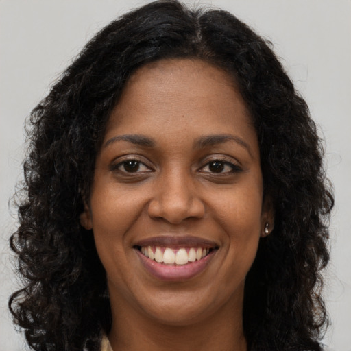 Joyful black young-adult female with long  brown hair and brown eyes