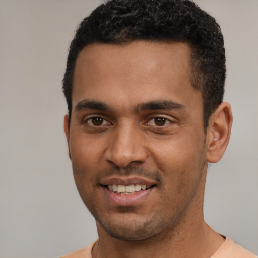 Joyful black young-adult male with short  black hair and brown eyes