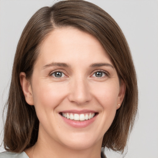 Joyful white young-adult female with medium  brown hair and grey eyes