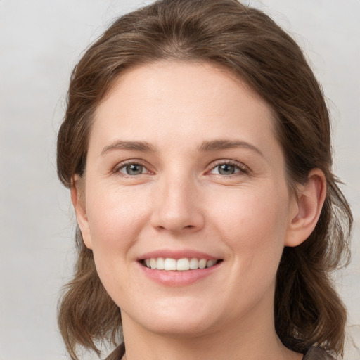 Joyful white young-adult female with medium  brown hair and grey eyes