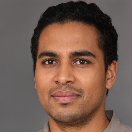 Joyful latino young-adult male with short  black hair and brown eyes
