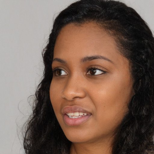 Joyful black young-adult female with long  black hair and brown eyes