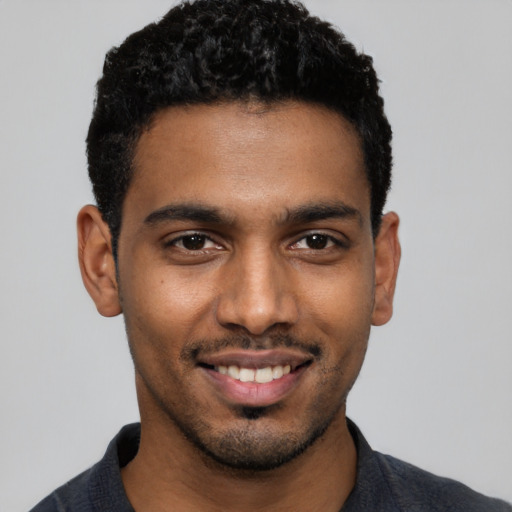 Joyful black young-adult male with short  black hair and brown eyes