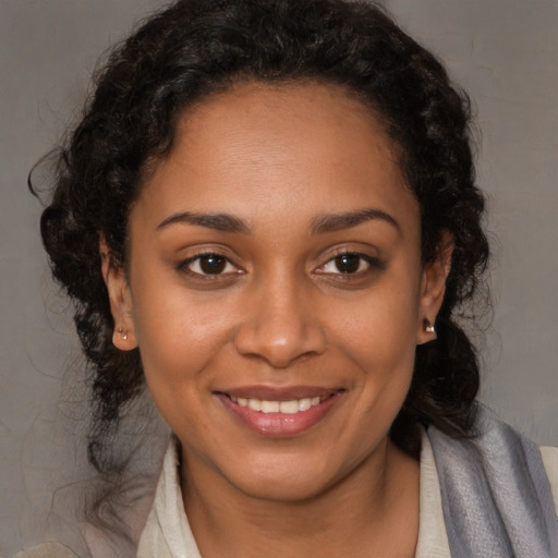 Joyful black young-adult female with long  brown hair and brown eyes