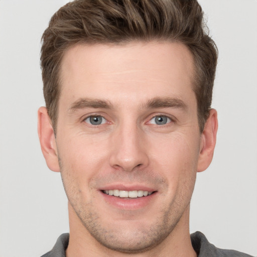 Joyful white young-adult male with short  brown hair and grey eyes